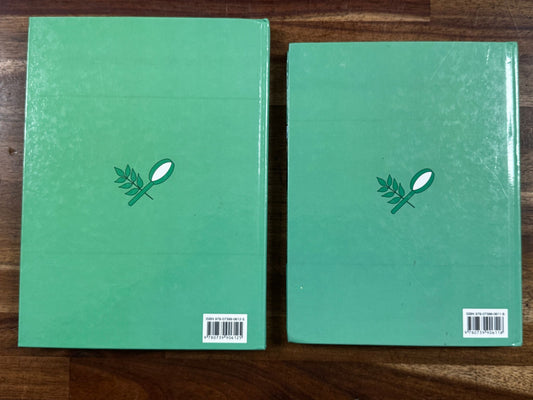 Two green books with a logo on a wooden surface